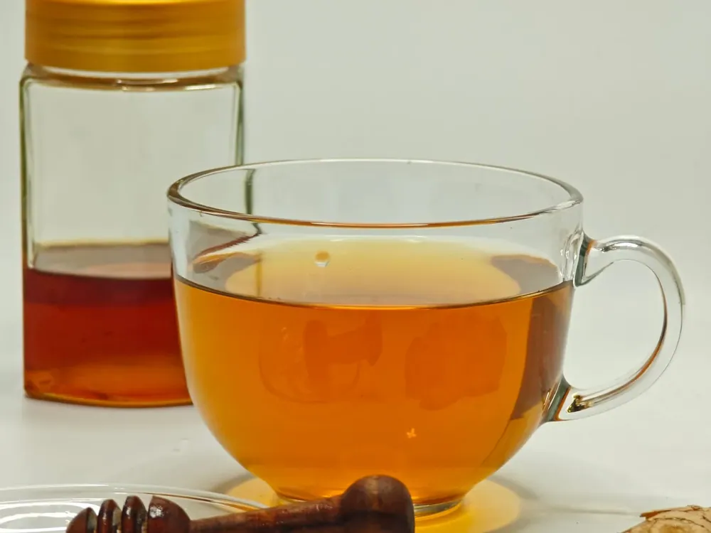 Tasse d'infusion, pot de miel avec sa cuillère en bois et gingembre frais