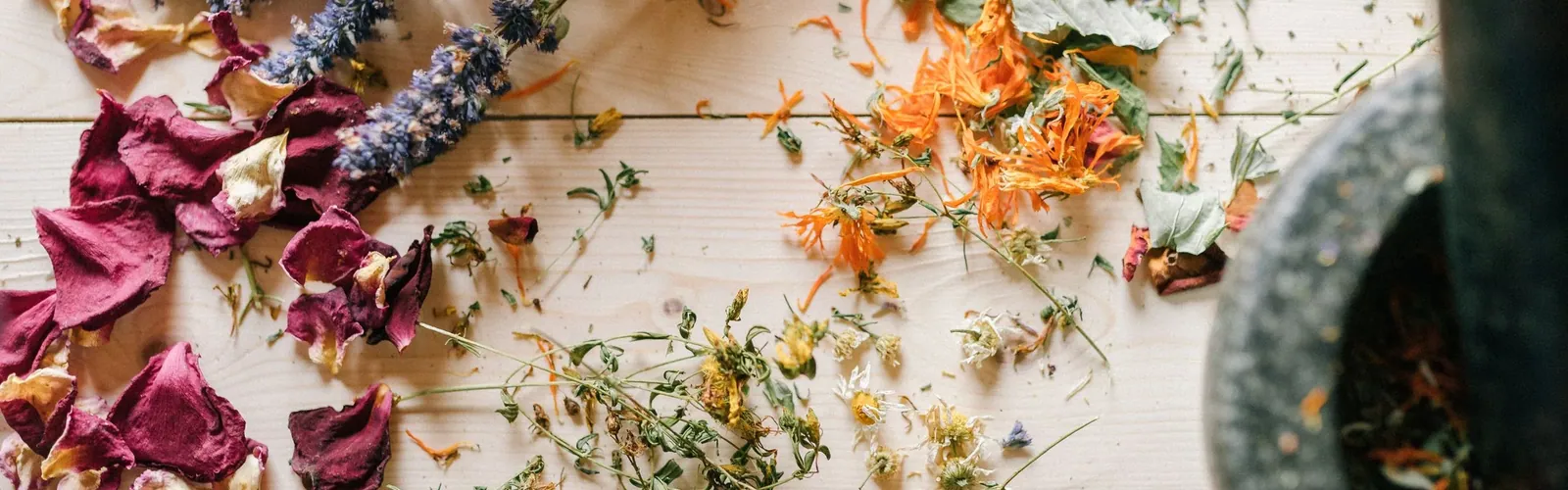 Herbes et fleurs séchées avec un mortier sur une table en bois clair